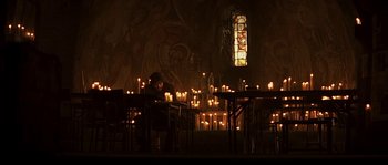 Movie still from “Reign of Fire” (2002), directed by Rob Bowman – A man sitting at a table in front of candles; Wide shot, High angle