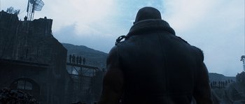 Movie still from “Reign of Fire” (2002), directed by Rob Bowman – A man in a leather jacket looking out over a bridge; Wide shot, Low angle