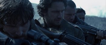 Movie still from “Reign of Fire” (2002), directed by Rob Bowman – A group of men standing next to each other holding guns; Close Up shot, Over the shoulder angle