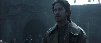 Movie still from “Reign of Fire” (2002), directed by Rob Bowman – A person wearing a trench coat; Close Up shot, Low angle