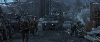 Movie still from “Reign of Fire” (2002), directed by Rob Bowman – A group of men standing next to each other near an army vehicle; Wide shot, High angle