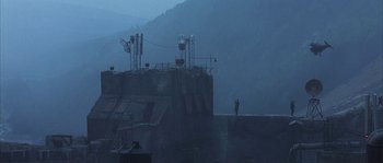 Movie still from “Reign of Fire” (2002), directed by Rob Bowman – A man standing on a ledge in the middle of the night; Extreme Wide shot, Low angle