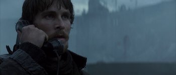 Movie still from “Reign of Fire” (2002), directed by Rob Bowman – A man is holding a microphone in front of a castle; Close Up shot, Over the shoulder angle