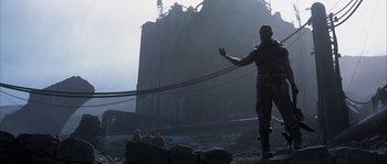 Movie still from “Reign of Fire” (2002), directed by Rob Bowman – A man standing on top of a mountain holding a rope; Medium shot, Low angle