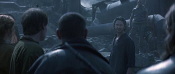 Movie still from “Reign of Fire” (2002), directed by Rob Bowman – A man standing next to another man in a field; Medium shot, Over the shoulder angle