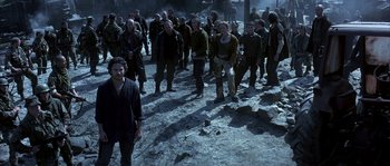 Movie still from “Reign of Fire” (2002), directed by Rob Bowman – A group of people standing on top of a dirt field; Wide shot, High angle