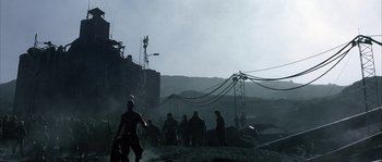 Movie still from “Reign of Fire” (2002), directed by Rob Bowman – A group of people standing next to power lines on top of a hill; Extreme Wide shot, Low angle