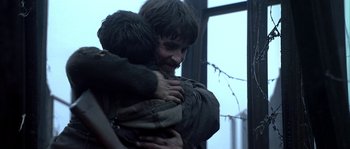 Movie still from “Reign of Fire” (2002), directed by Rob Bowman – A man hugging another man in front of a window; Close Up shot, Over the shoulder angle