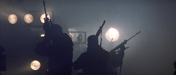 Movie still from “Reign of Fire” (2002), directed by Rob Bowman – A group of people in a room holding guns; Wide shot, Low angle