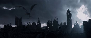 Movie still from “Reign of Fire” (2002), directed by Rob Bowman – A dark picture of a castle with a dragon flying over it; Extreme Wide shot, Low angle