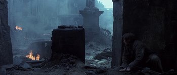 Movie still from “Reign of Fire” (2002), directed by Rob Bowman – A man standing in a room that has been destroyed; Wide shot, High angle