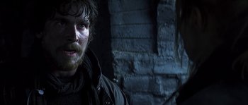 Movie still from “Reign of Fire” (2002), directed by Rob Bowman – A man with a beard is standing in front of a brick wall; Close Up shot, Low angle