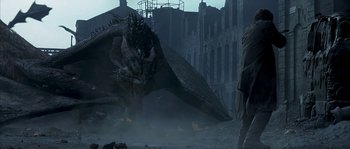 Movie still from “Reign of Fire” (2002), directed by Rob Bowman – A man standing in front of a large dragon; Wide shot, Low angle