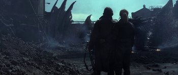 Movie still from “Reign of Fire” (2002), directed by Rob Bowman – A couple of people standing next to each other near some rocks; Wide shot, Over the shoulder angle