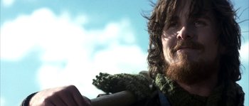 Movie still from “Reign of Fire” (2002), directed by Rob Bowman – A man with long hair and a beard is smiling; Close Up shot, Low angle