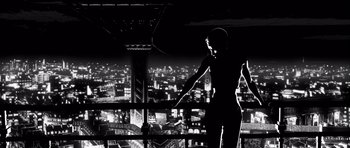 Movie still from “Renaissance” (2006), directed by Christian Volckman – A man standing on a balcony looking out over a city at night; Wide shot, Low angle