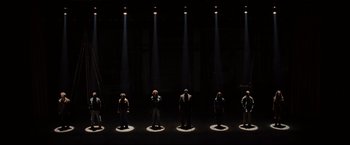 Movie still from “Rent” (2005), directed by Chris Columbus – A group of people standing in the middle of a stage; Extreme Wide shot, Overhead angle