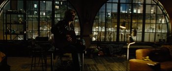 Movie still from “Rent” (2005), directed by Chris Columbus – A man sitting on a chair playing a guitar; Wide shot, High angle