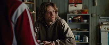 Movie still from “Rent” (2005), directed by Chris Columbus – A man sitting at a table in a living room; Close Up shot, Over the shoulder angle