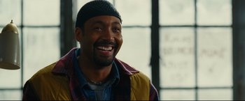 Movie still from “Rent” (2005), directed by Chris Columbus – A man smiles while wearing a hat and a jacket; Close Up shot, Over the shoulder angle