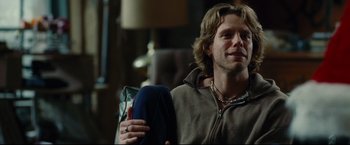 Movie still from “Rent” (2005), directed by Chris Columbus – A man sitting on a couch holding a bag; Close Up shot, Over the shoulder angle