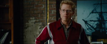 Movie still from “Rent” (2005), directed by Chris Columbus – A man in a red and white jacket standing in front of a brick wall; Close Up shot, Over the shoulder angle