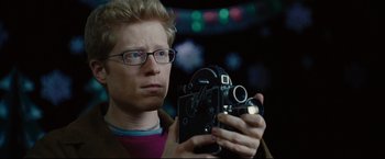 Movie still from “Rent” (2005), directed by Chris Columbus – A man holding an old camera in his hands; Close Up shot, Low angle