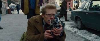 Movie still from “Rent” (2005), directed by Chris Columbus – A man taking a picture with a camera on the street; Close Up shot, High angle