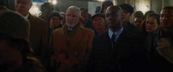 Movie still from “Rent” (2005), directed by Chris Columbus – A group of men standing next to each other in a crowd; Medium shot, Over the shoulder angle