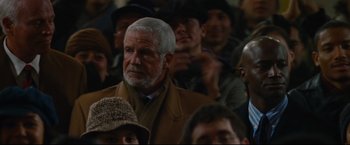 Movie still from “Rent” (2005), directed by Chris Columbus – An older man is sitting in a crowd of people; Close Up shot, Over the shoulder angle