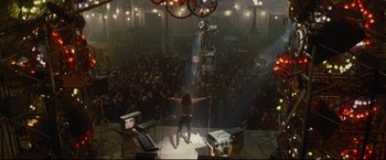 Movie still from “Rent” (2005), directed by Chris Columbus – A crowd of people watching a woman on stage; Wide shot, Overhead angle