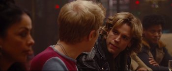 Movie still from “Rent” (2005), directed by Chris Columbus – Two young men talking to each other in front of a red light; Close Up shot, Over the shoulder angle