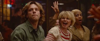 Movie still from “Rent” (2005), directed by Chris Columbus – A man and a woman are waving at the camera; Close Up shot, Over the shoulder angle