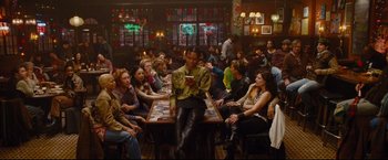 Movie still from “Rent” (2005), directed by Chris Columbus – A group of people sitting around a table with a cell phone; Wide shot, High angle