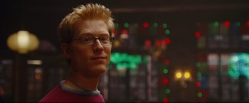 Movie still from “Rent” (2005), directed by Chris Columbus – A person wearing glasses with lights in the background; Close Up shot, Over the shoulder angle