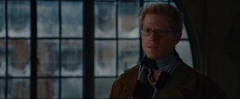 Movie still from “Rent” (2005), directed by Chris Columbus – A man wearing glasses standing in front of a window; Close Up shot, Over the shoulder angle