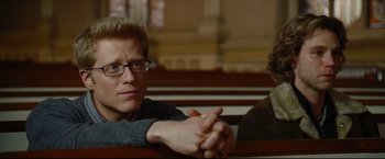 Movie still from “Rent” (2005), directed by Chris Columbus – A man sitting next to another man on a bench; Close Up shot, Over the shoulder angle