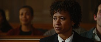 Movie still from “Rent” (2005), directed by Chris Columbus – A woman in a suit and tie looking to her left; Close Up shot, Over the shoulder angle