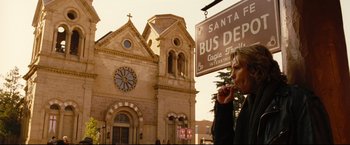 Movie still from “Rent” (2005), directed by Chris Columbus – A person standing in front of a building with a clock; Wide shot, Low angle
