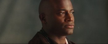 Movie still from “Rent” (2005), directed by Chris Columbus – A man with a shaved head and a brown jacket looking to his left; Close Up shot, Low angle