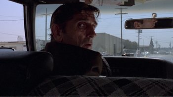 Movie still from “Repo Man” (1984), directed by Alex Cox – A man sitting in the passenger seat of a car; Close Up shot, Low angle