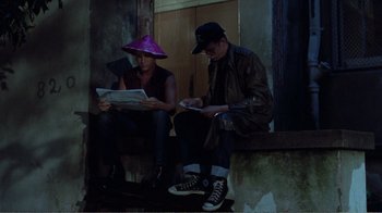 Movie still from “Repo Man” (1984), directed by Alex Cox – A man and a woman sitting next to each other on steps; Medium shot, High angle