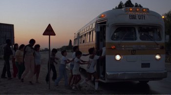Movie still from “Repo Man” (1984), directed by Alex Cox – A group of people getting off a bus at dusk; Wide shot, Low angle