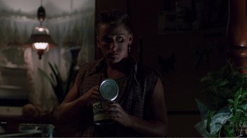 Movie still from “Repo Man” (1984), directed by Alex Cox – A person holding a can of food in a dark room; Medium shot, Low angle