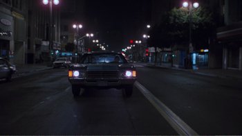 Movie still from “Repo Man” (1984), directed by Alex Cox – A car driving down a street at night; Extreme Wide shot, Low angle