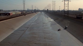 Movie still from “Repo Man” (1984), directed by Alex Cox – A body of water that has water in it; Extreme Wide shot, High angle