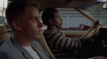 Movie still from “Repo Man” (1984), directed by Alex Cox – Two men are driving in the back of a car; Close Up shot, Low angle