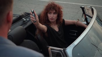 Movie still from “Repo Man” (1984), directed by Alex Cox – A woman in a car holding a cell phone; Close Up shot, High angle