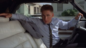 Movie still from “Repo Man” (1984), directed by Alex Cox – A man in a suit and tie sitting in the back seat of a car; Close Up shot, Low angle