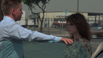 Movie still from “Repo Man” (1984), directed by Alex Cox – A young girl leaning against a fence with an older man touching her shoulder; Medium shot, Over the shoulder angle